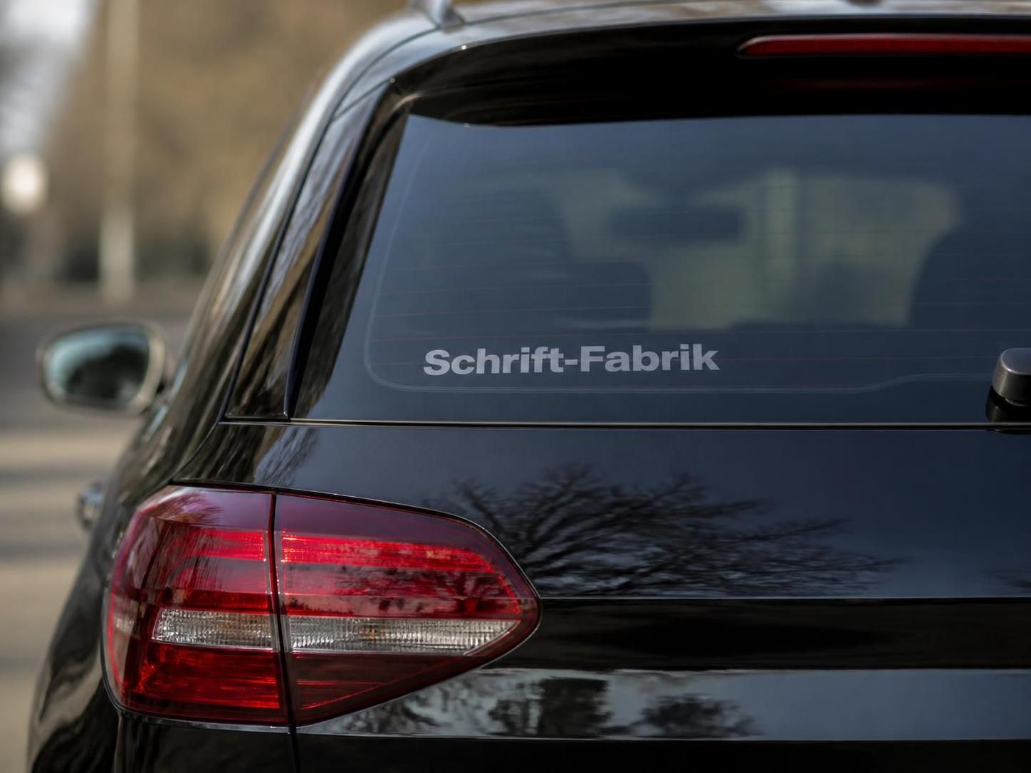 Dunkler PKW mit freistehendem Aufkleber auf der Heckscheibe